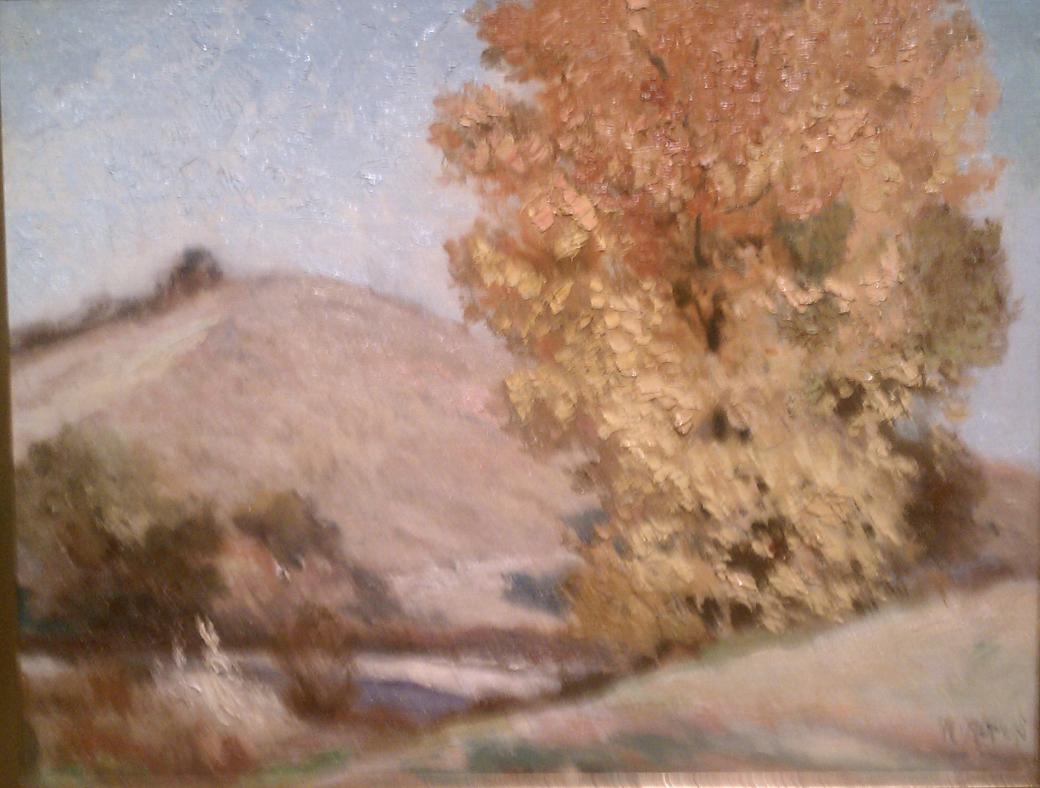 Tan hills with orange and yellow tree.