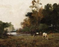 Cows grazing by a river, dark brown ground below and dark green trees behind the cows.