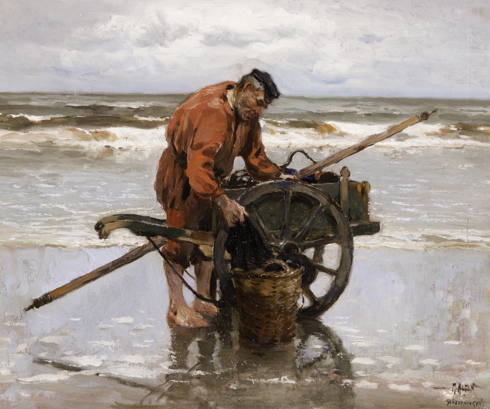 Man in red jacket standing on the beach next to a wooden cart.