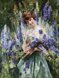 Image of a young girl in a green dress surrounded by and holding purple flowers.