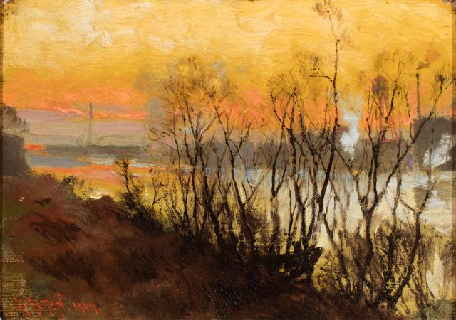 Leafless trees in foreground, river behind and bright sunset in background.
