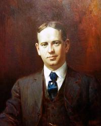 A portrait of a young gentleman in a brown suit and blue tie facing forwards.
