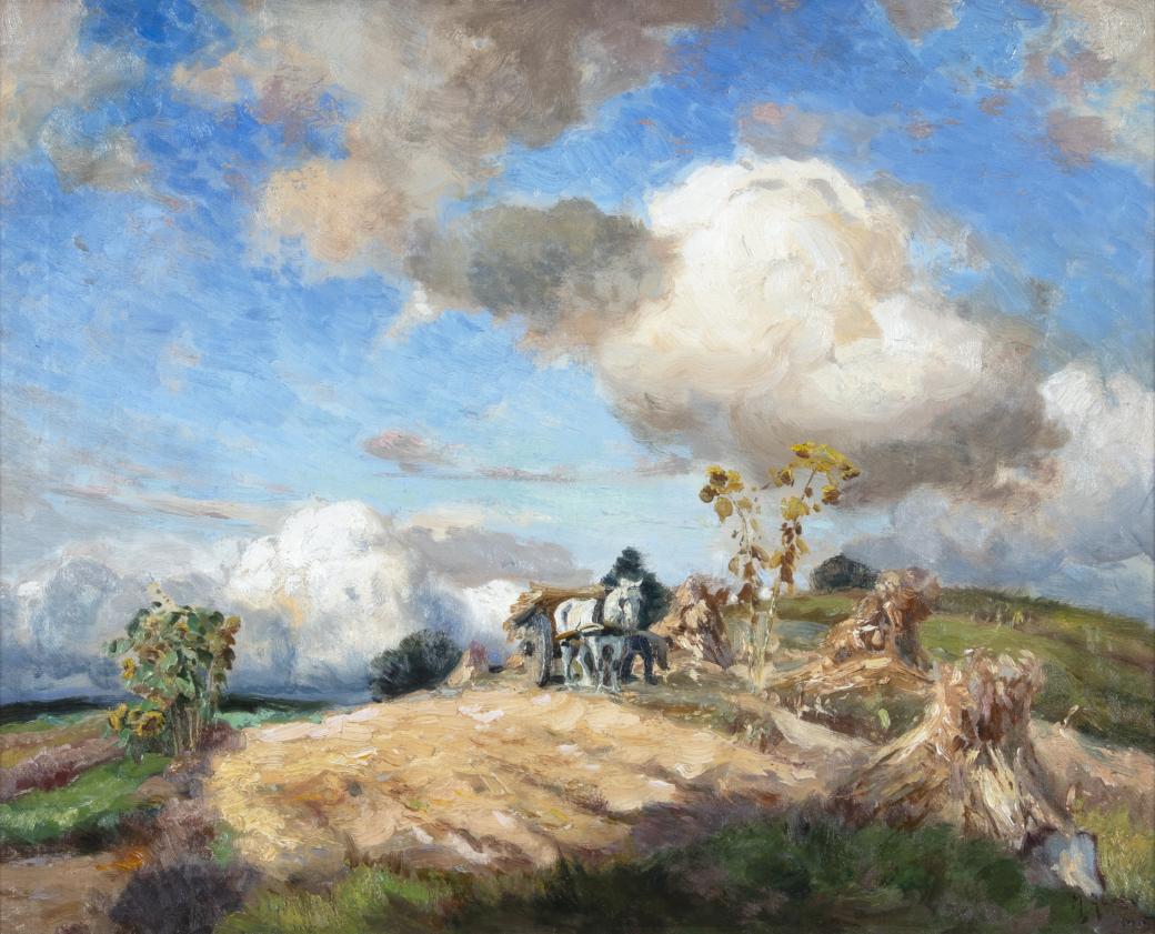 White horse pulling a cart on the side of a field.