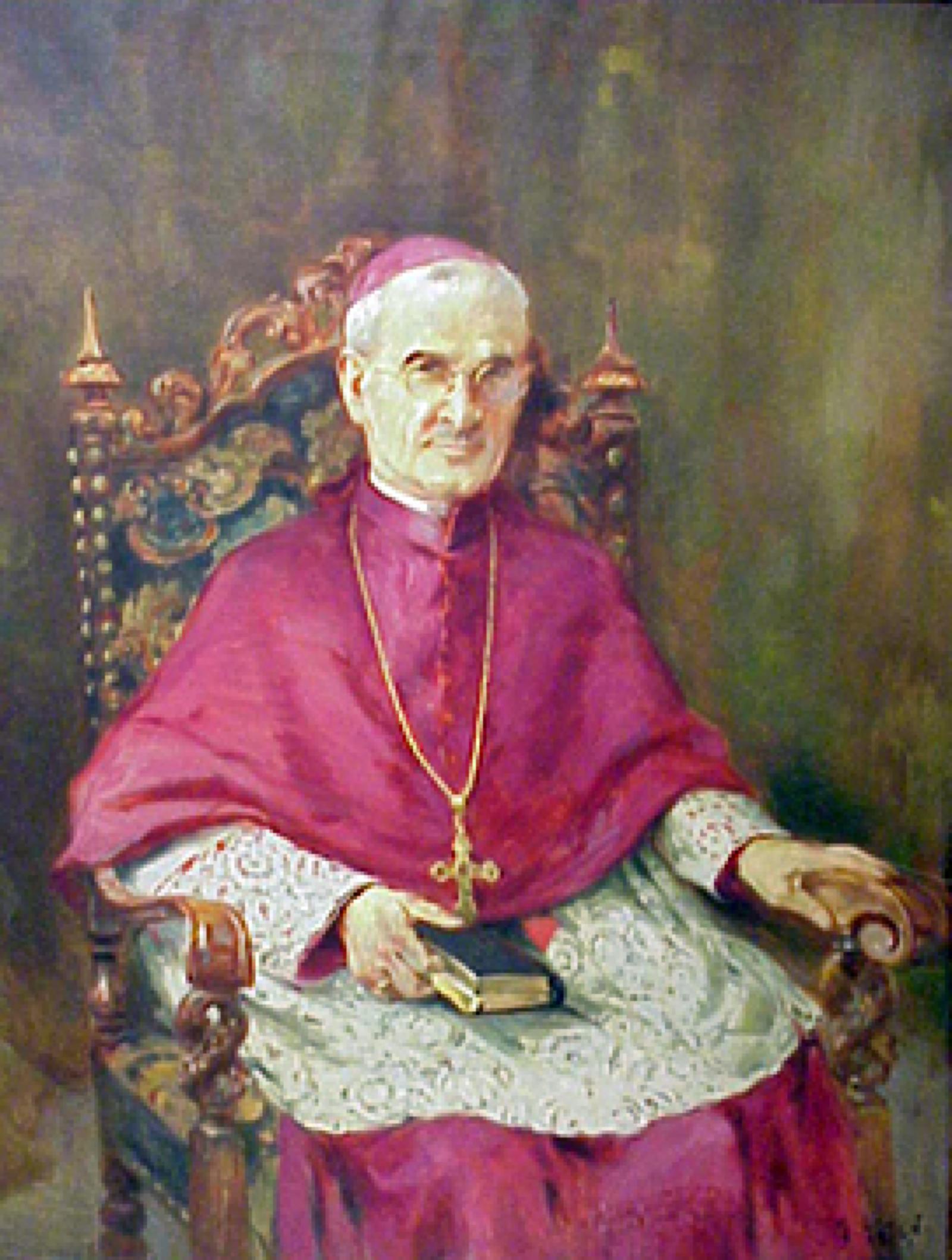Bishop in red wearing a gold cross sitting in chair with Bible in lap.