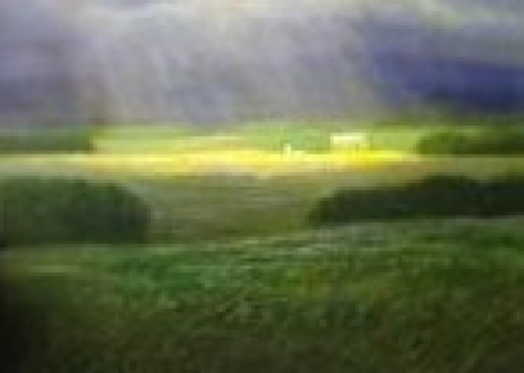 Grass plains with clouded sky showing sunlight through the center.