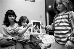 Mary + her daughters holding a family portrait with their father, Minneapolis, 1987