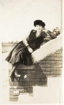 Untitled (Woman Perched Playfully Atop Brick Wall)