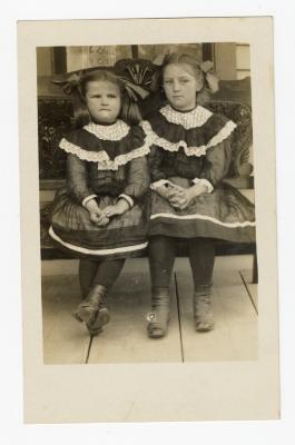 Untitled (Two girls sitting on bench in matching outfits)